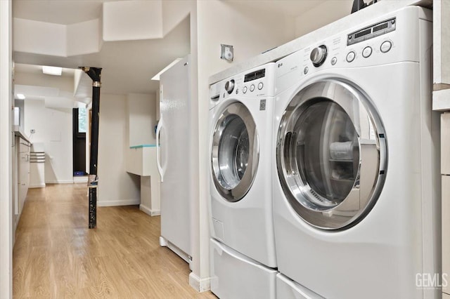 laundry room with baseboards, laundry area, light wood finished floors, and washing machine and clothes dryer