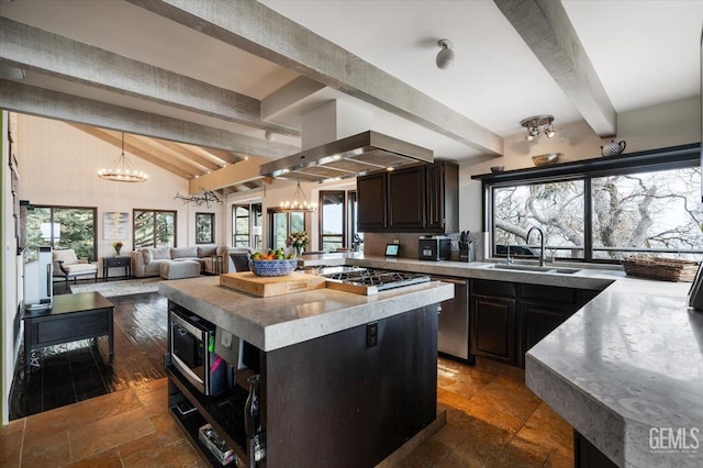 kitchen with stone tile flooring, range hood, a chandelier, a sink, and appliances with stainless steel finishes