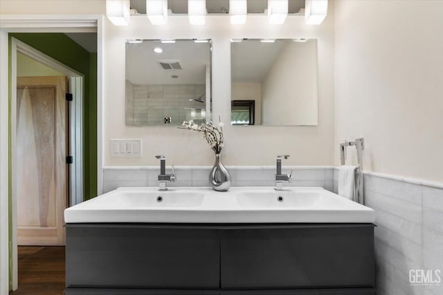 bathroom featuring visible vents, a sink, wainscoting, and double vanity