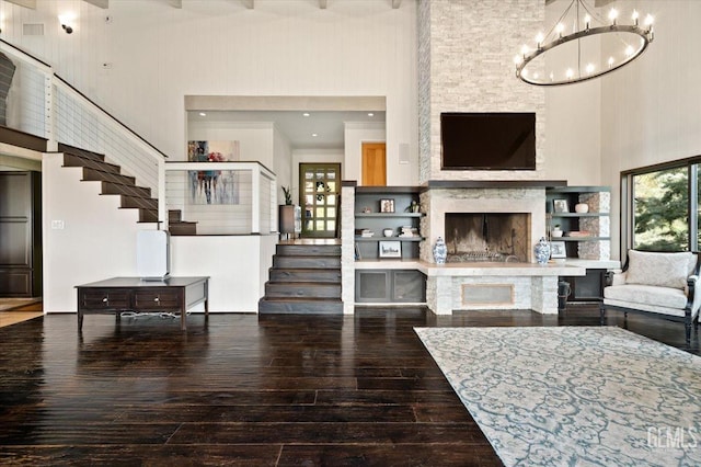living area with stairway, an inviting chandelier, wood-type flooring, and a towering ceiling