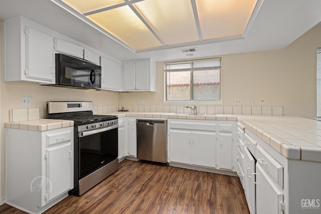 kitchen featuring dark hardwood / wood-style floors, tile counters, kitchen peninsula, stainless steel appliances, and white cabinets