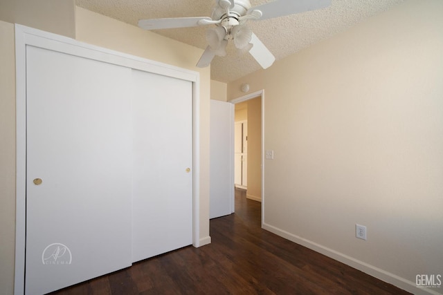 unfurnished bedroom featuring ceiling fan, dark hardwood / wood-style flooring, a closet, and a textured ceiling