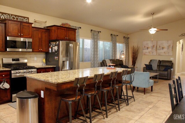 9512 Four Pines Dr, Shafter, CA 93263 - kitchen featuring stainless steel appliances, light tile patterned floors, decorative backsplash, a kitchen island, and light stone counters