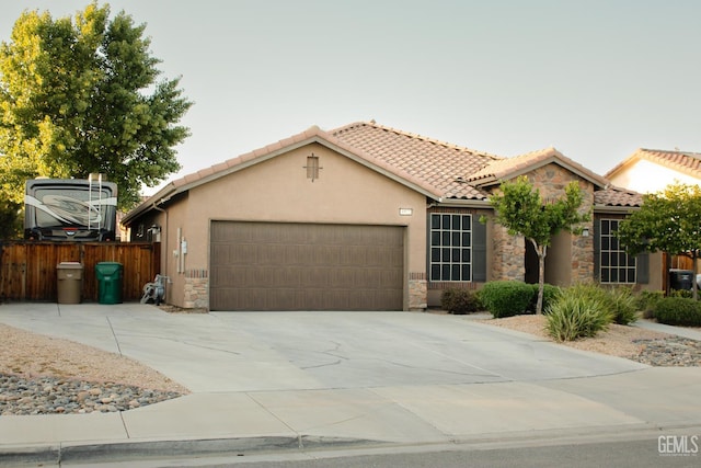 9512 Four Pines Dr, Shafter, CA 93263 - view of front of house with an attached garage, stone siding, fence, and a tiled roof