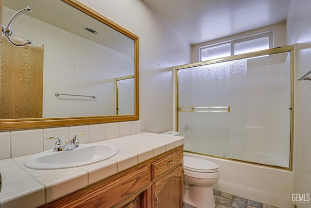 full bathroom with combined bath / shower with glass door, vanity, tasteful backsplash, and toilet