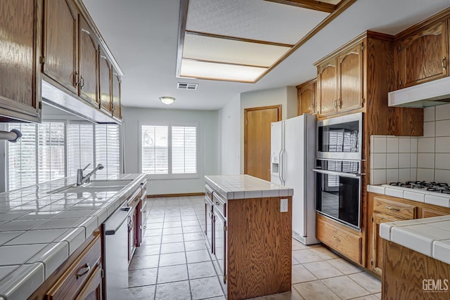 kitchen featuring decorative backsplash, tile counters, a center island, and white appliances