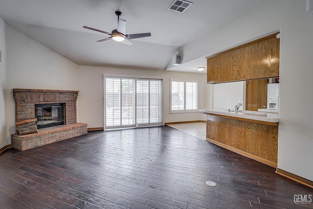 kitchen with vaulted ceiling, ceiling fan, white fridge with ice dispenser, a fireplace, and tile counters