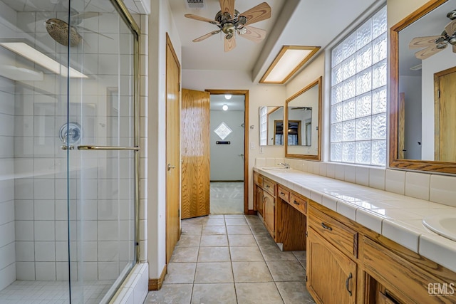 bathroom with ceiling fan, tile patterned flooring, vanity, and walk in shower