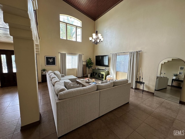 living area with arched walkways, wood ceiling, baseboards, high vaulted ceiling, and a notable chandelier