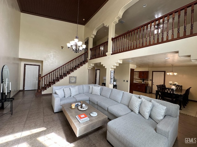 living room featuring baseboards, stairway, a notable chandelier, and a high ceiling