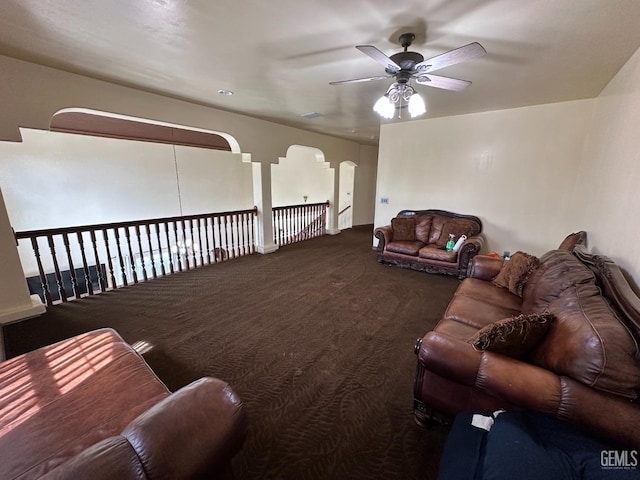 living area with carpet, a ceiling fan, and arched walkways