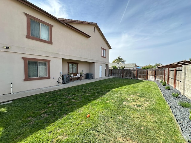 view of yard with a fenced backyard, central air condition unit, and a patio area