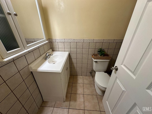 bathroom featuring tile patterned flooring, wainscoting, tile walls, toilet, and vanity