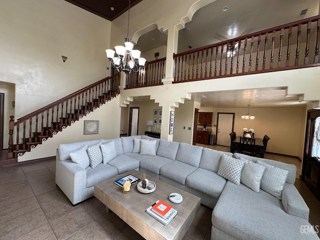 living room with a towering ceiling, a chandelier, tile patterned flooring, and stairs