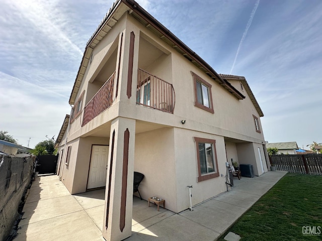 rear view of house with a patio, fence, stucco siding, and central air condition unit