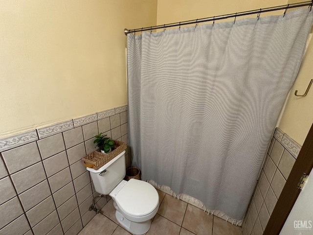 full bath featuring tile walls, wainscoting, toilet, and tile patterned flooring