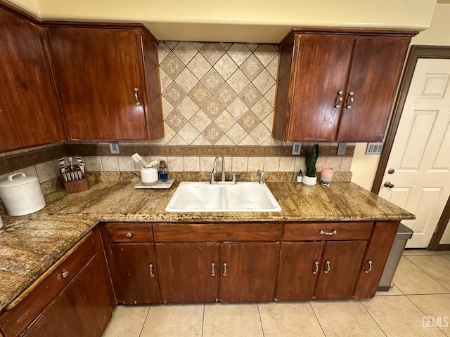 kitchen with light tile patterned floors, stone counters, a sink, and tasteful backsplash