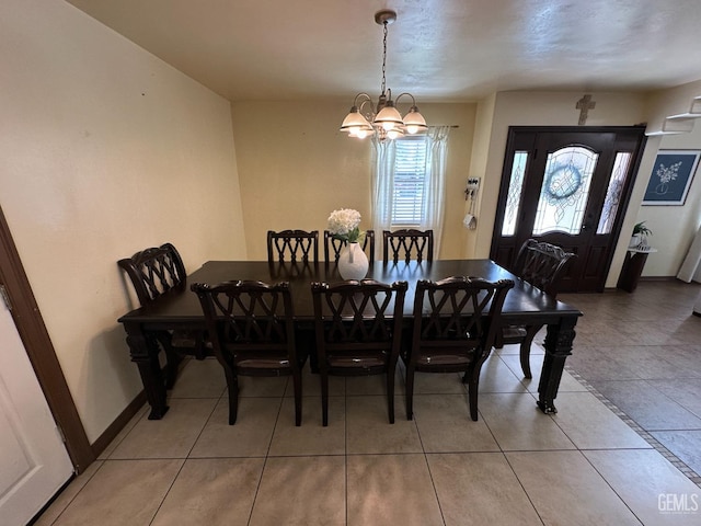 dining space featuring tile patterned floors, a chandelier, and baseboards