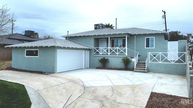 view of front of home with stucco siding, central air condition unit, a porch, concrete driveway, and a garage