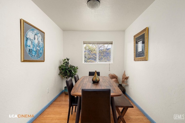 dining space with hardwood / wood-style floors and a textured ceiling