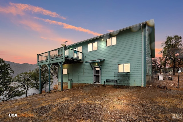 back house at dusk with a mountain view and a balcony