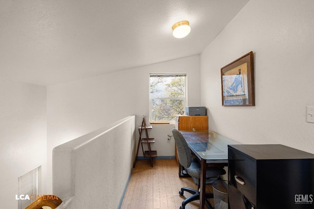 office area featuring a textured ceiling, hardwood / wood-style flooring, and lofted ceiling