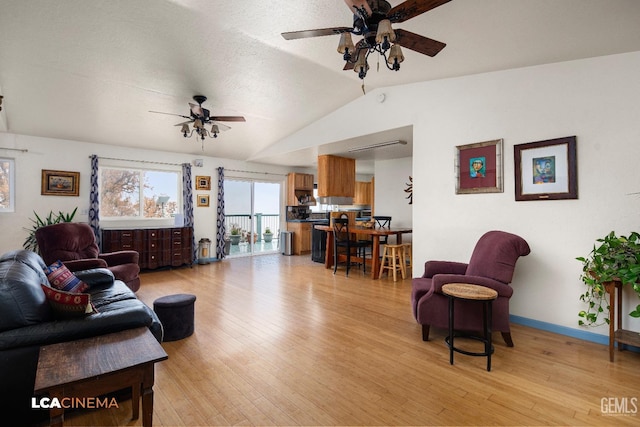 living room with a textured ceiling, light wood-type flooring, ceiling fan, and lofted ceiling