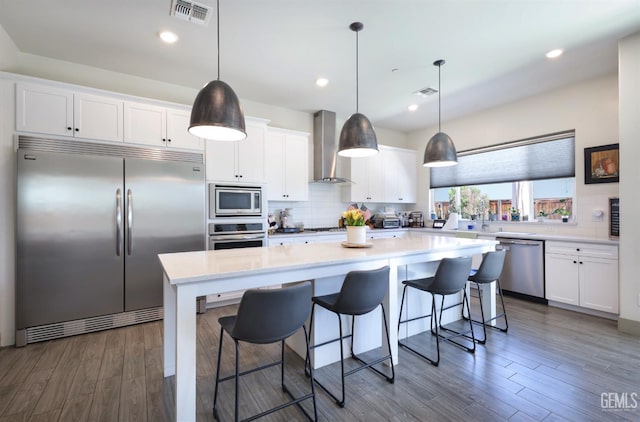 9108 Manor Forest Ln, Shafter, CA 93263 - kitchen with built in appliances, wall chimney range hood, dark wood-style floors, white cabinetry, and recessed lighting