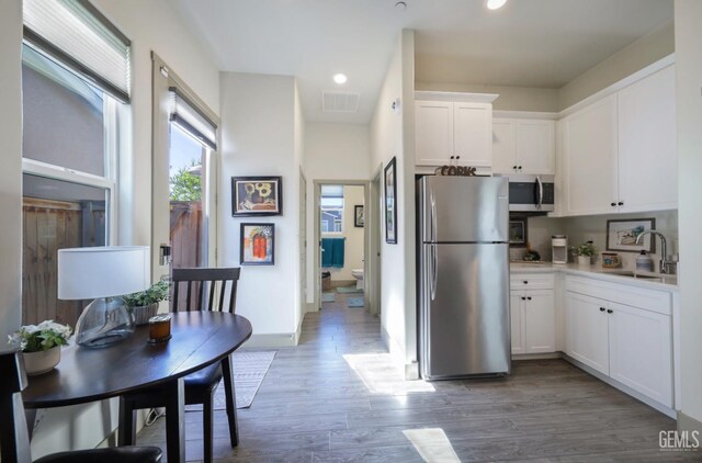 9108 Manor Forest Ln, Shafter, CA 93263 - kitchen with stainless steel appliances, white cabinetry, light wood finished floors, light countertops, and recessed lighting