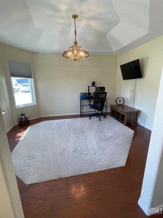 office area featuring a raised ceiling, dark wood-type flooring, and a notable chandelier