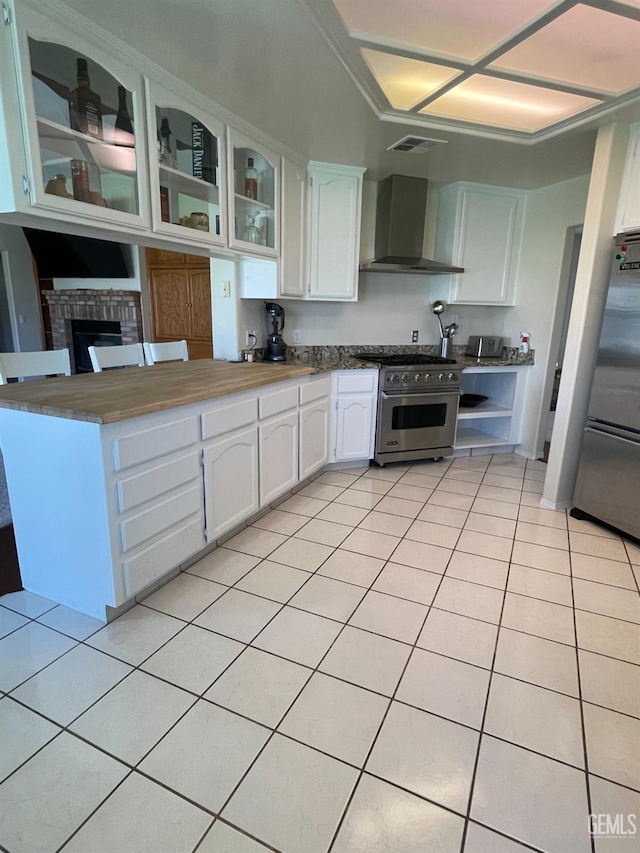 kitchen featuring appliances with stainless steel finishes, light tile patterned floors, white cabinets, and wall chimney exhaust hood