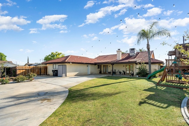 view of front of property with a playground, central AC, and a front lawn