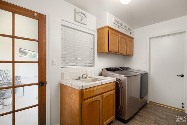 washroom with separate washer and dryer, sink, dark hardwood / wood-style floors, and cabinets