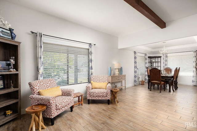 sitting room featuring light hardwood / wood-style flooring, a notable chandelier, plenty of natural light, and beamed ceiling