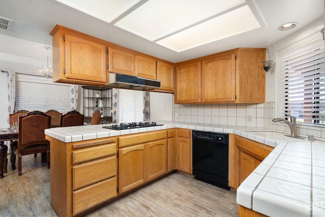 kitchen with sink, tasteful backsplash, tile counters, black appliances, and kitchen peninsula