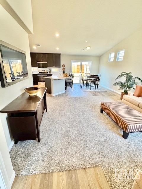 kitchen featuring dark brown cabinetry, sink, vaulted ceiling, and light hardwood / wood-style flooring