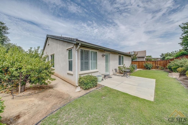 rear view of house featuring a patio area and a yard