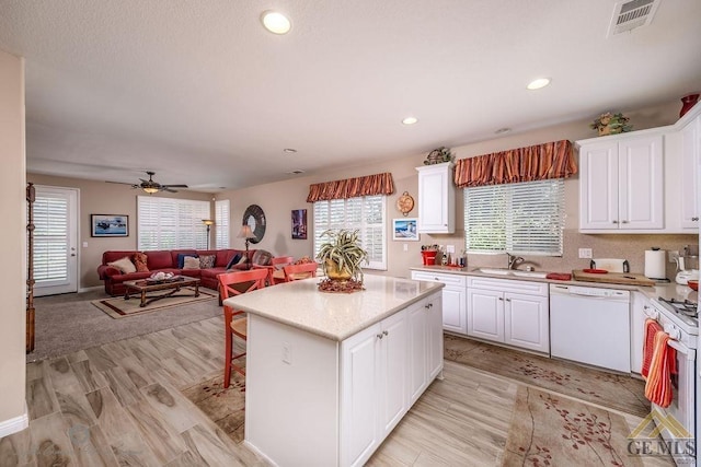 kitchen featuring white appliances, a center island, white cabinetry, and sink