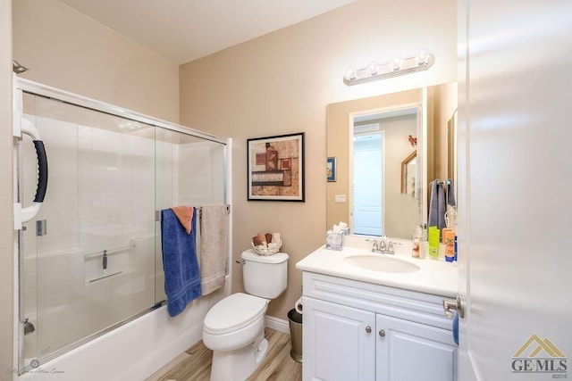 full bathroom featuring vanity, hardwood / wood-style flooring, toilet, and bath / shower combo with glass door