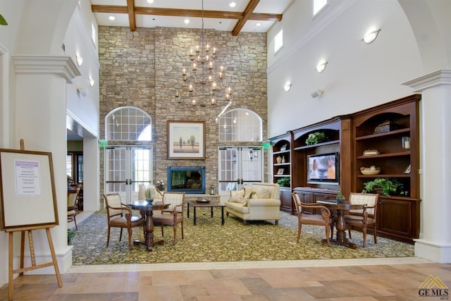 living room featuring a towering ceiling, beamed ceiling, a chandelier, and french doors