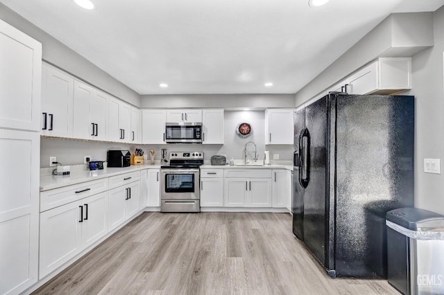 kitchen with white cabinets, light wood-type flooring, stainless steel appliances, and sink