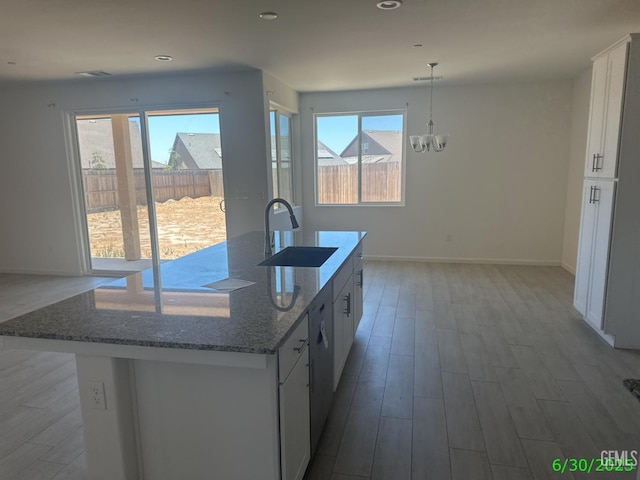 716 Montejo Ct, Delano, CA 93215 - kitchen with wood finished floors, a kitchen island with sink, a chandelier, white cabinetry, and stone counters