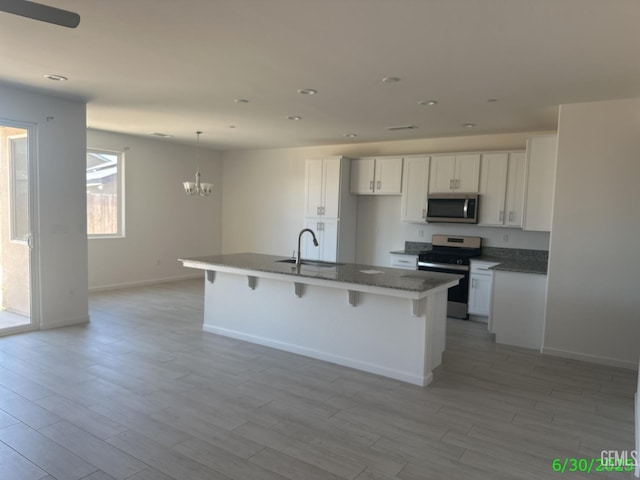 716 Montejo Ct, Delano, CA 93215 - kitchen featuring appliances with stainless steel finishes, light wood finished floors, a chandelier, white cabinets, and recessed lighting
