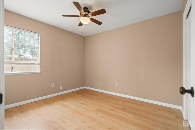 empty room featuring light wood finished floors, a ceiling fan, and baseboards