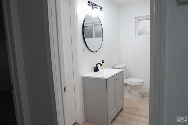 half bath featuring toilet, wood finished floors, and vanity