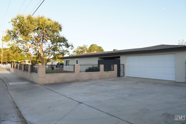 view of front of home with concrete driveway, an attached garage, a fenced front yard, and stucco siding