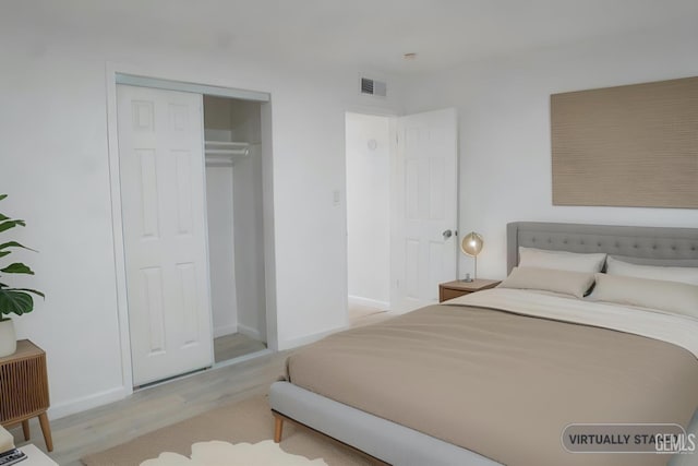 bedroom featuring a closet, visible vents, baseboards, and wood finished floors