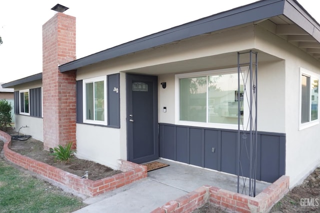 entrance to property featuring stucco siding and a chimney