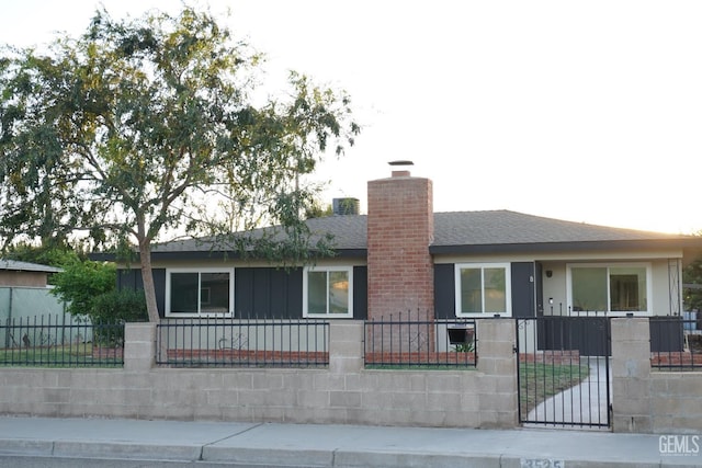 single story home featuring a fenced front yard, a chimney, roof with shingles, and a gate