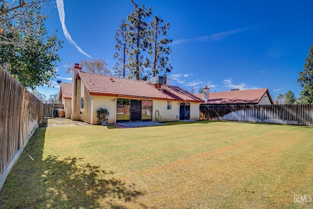 rear view of property with a yard, a fenced backyard, stucco siding, and a tiled roof